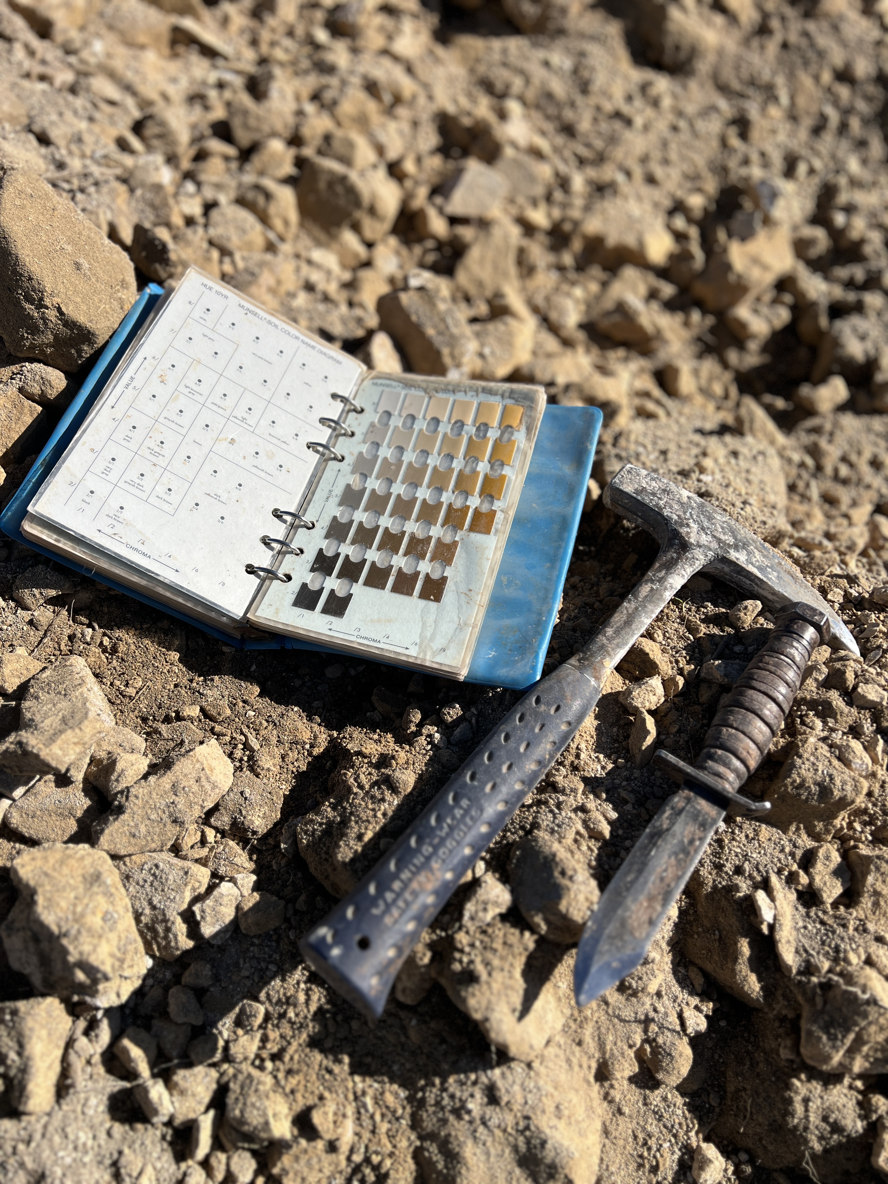Munsell soil color chart and rock hammer in the field